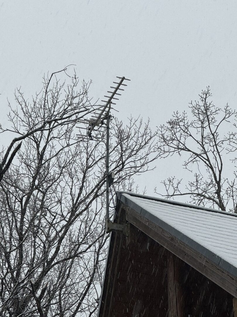 雪が降る中、屋根上に設置された施工前の既存アンテナのアップ