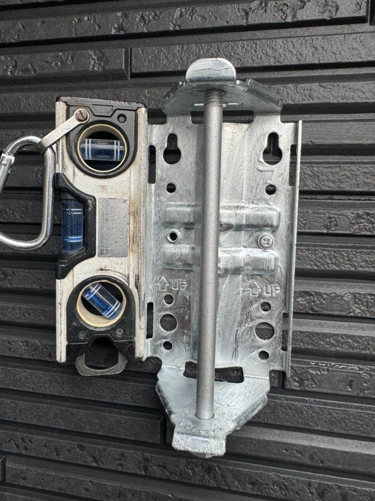 デザインアンテナ取り付け金具を水平器で調整し、ステンレスビスで固定している様子。