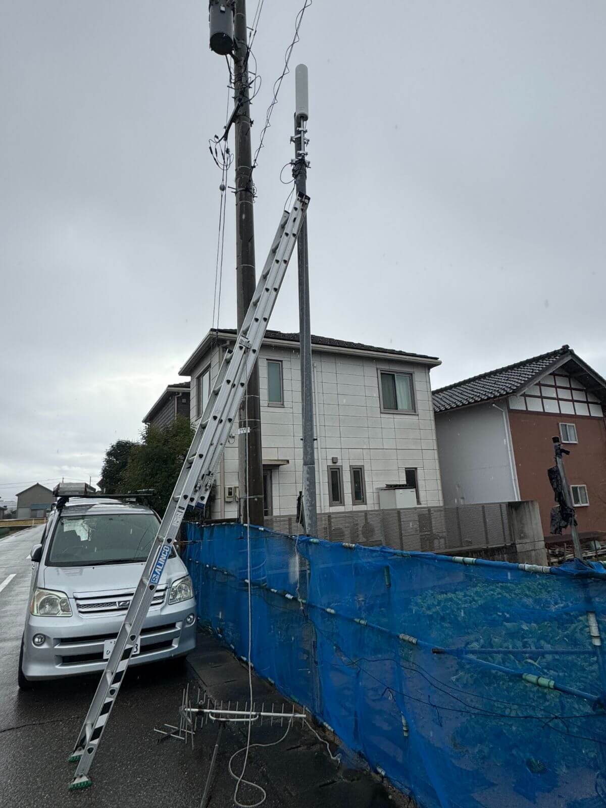 はしごを使って電柱にユニコーンアンテナを設置した施工風景（石川県金沢市M様邸）