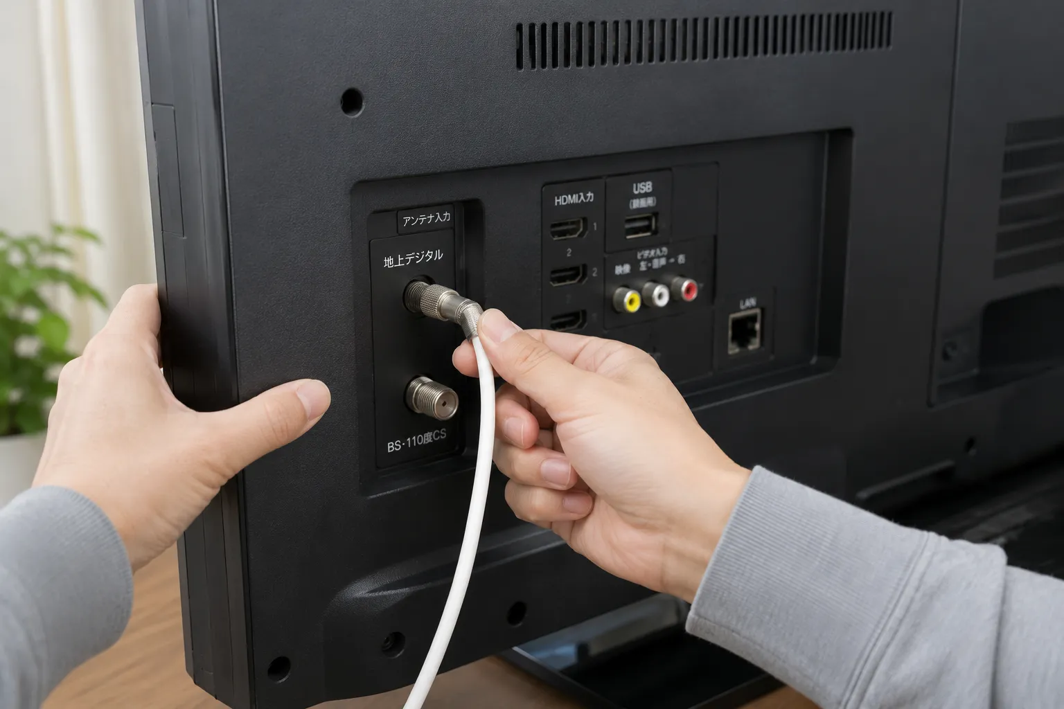 テレビ裏のアンテナケーブル接続を確認する様子