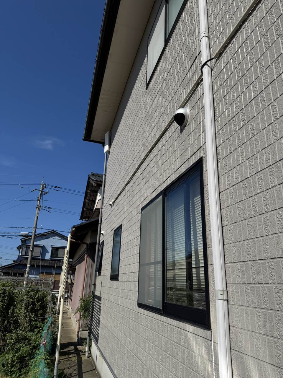 白いデザインアンテナを軒下の外壁に設置した母屋の外観
